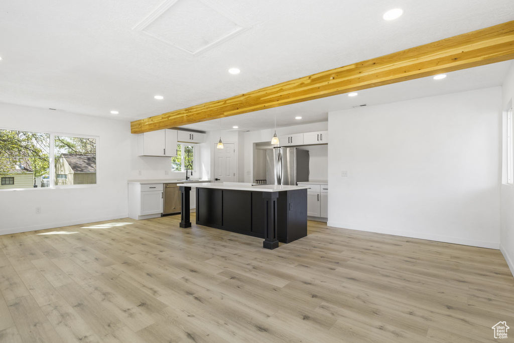 Kitchen with white cabinetry, light hardwood / wood-style floors, stainless steel appliances, and beamed ceiling