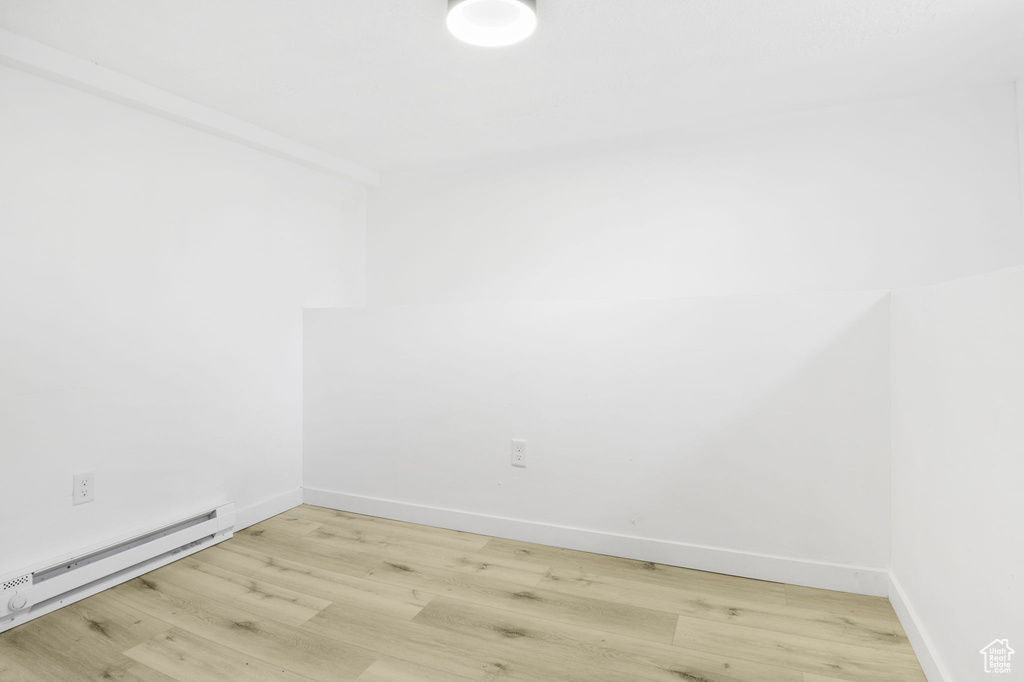 Empty room with light hardwood / wood-style flooring and a baseboard radiator