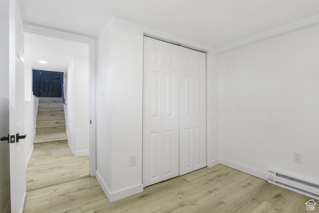 Interior space with a closet, light wood-type flooring, and baseboard heating