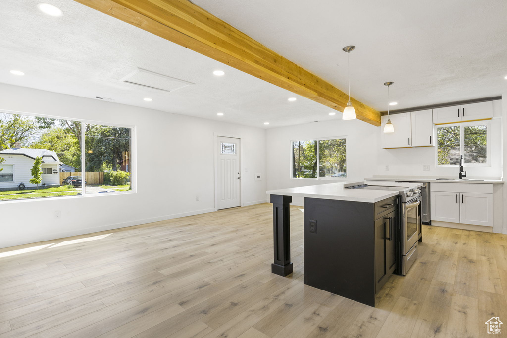 Kitchen with light wood-type flooring, a center island, stainless steel electric range, and white cabinetry