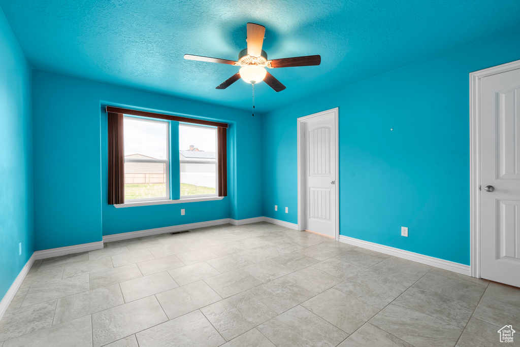 Tiled spare room with ceiling fan and a textured ceiling