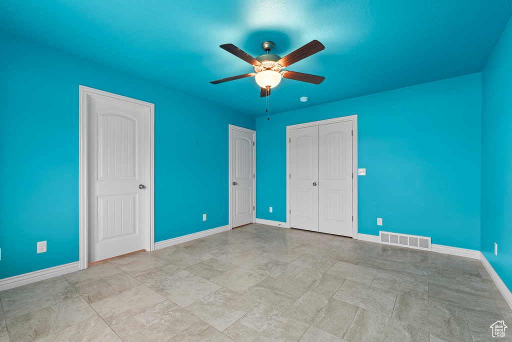 Unfurnished bedroom with ceiling fan and light tile flooring