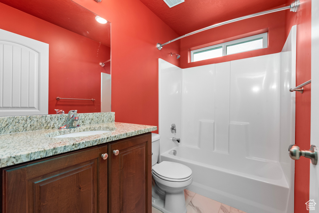 Full bathroom with washtub / shower combination, vanity, toilet, and tile flooring