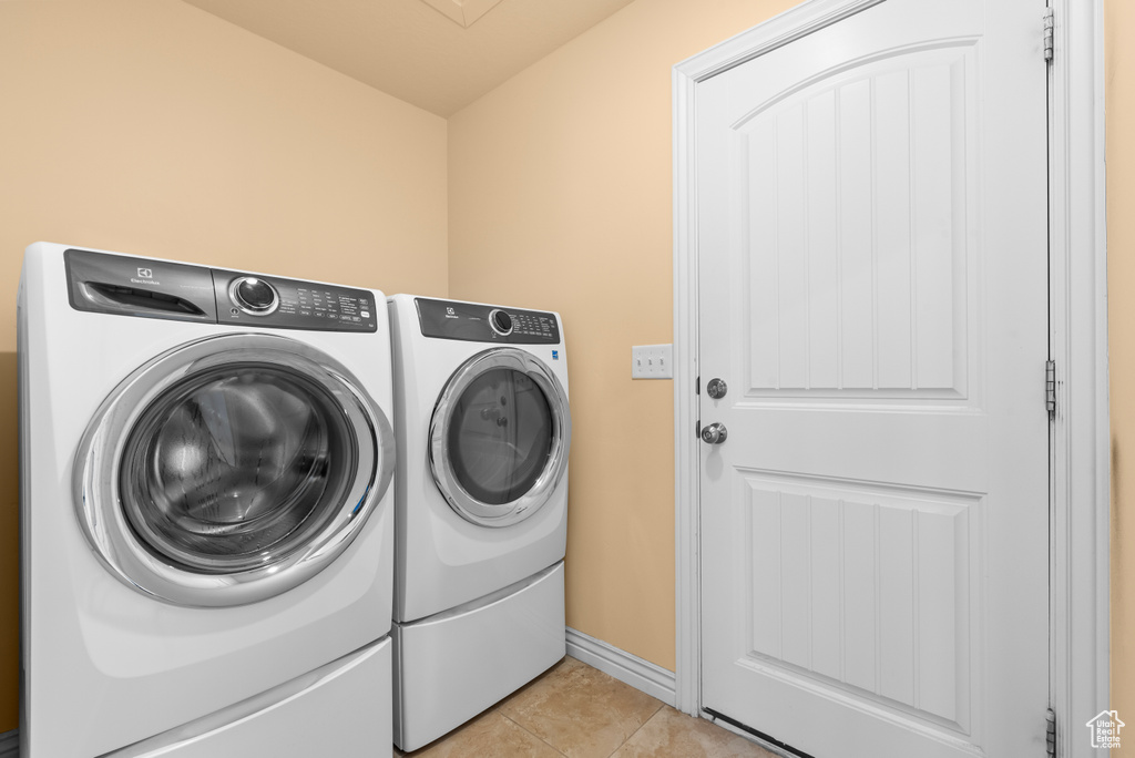 Clothes washing area with separate washer and dryer and light tile floors