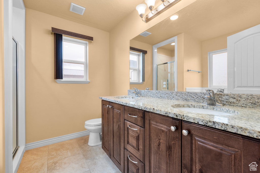 Bathroom featuring tile flooring, double vanity, toilet, and a wealth of natural light