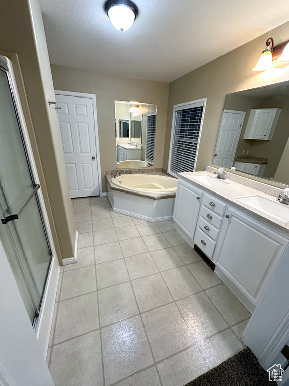 Bathroom featuring a washtub, tile flooring, and dual vanity