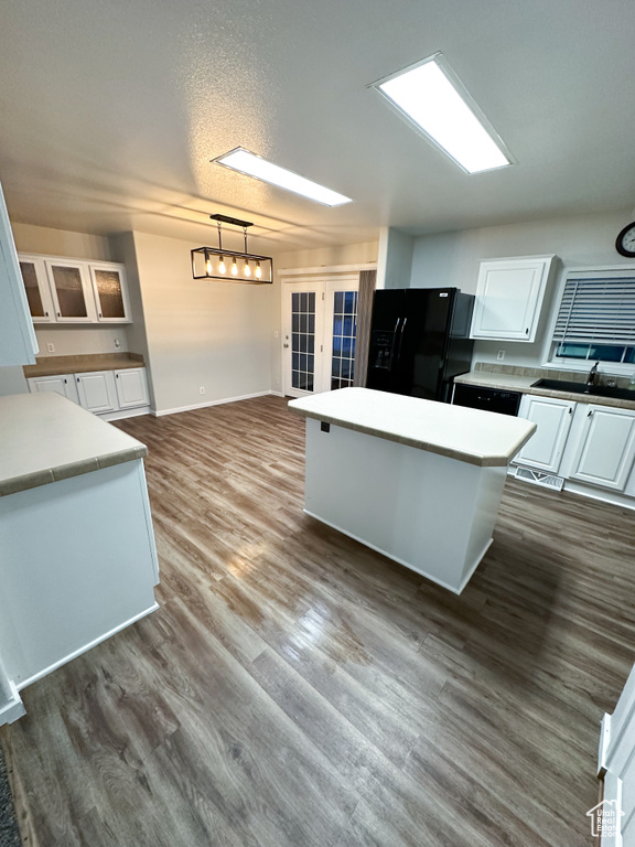 Kitchen featuring white cabinets, dark hardwood / wood-style flooring, and black fridge with ice dispenser