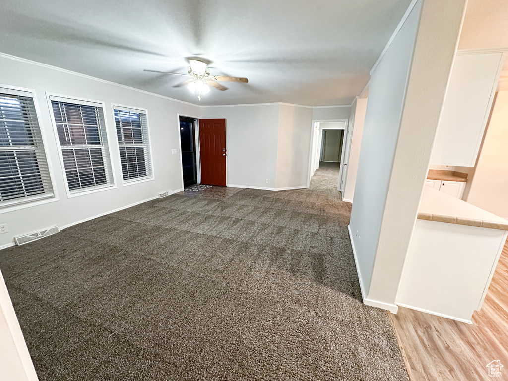 Carpeted empty room featuring ornamental molding and ceiling fan