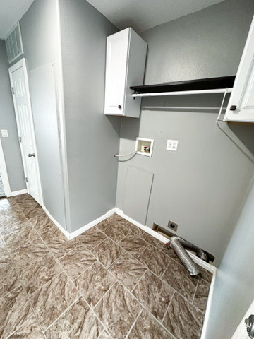 Clothes washing area featuring hookup for a washing machine, electric dryer hookup, cabinets, and light tile flooring