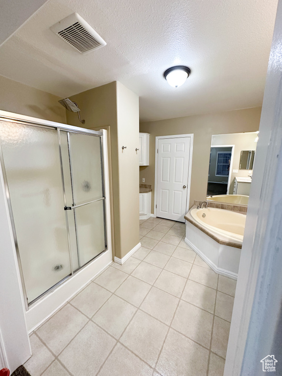 Bathroom with a textured ceiling, vanity, tile floors, and plus walk in shower