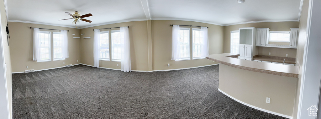 Carpeted spare room with ornamental molding, ceiling fan, and vaulted ceiling