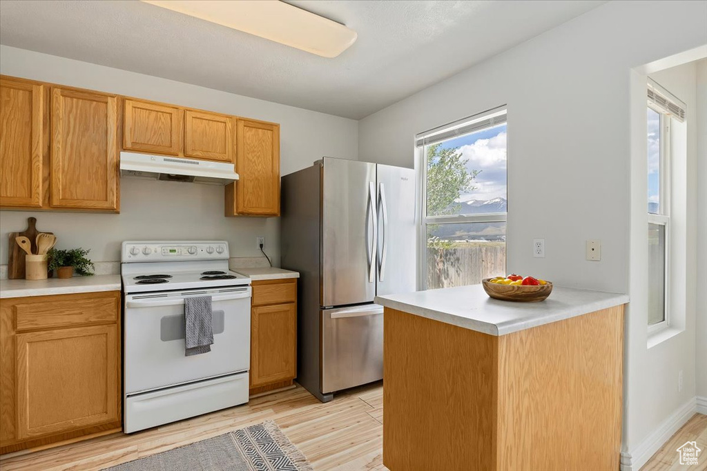 Kitchen with stainless steel fridge, light hardwood / wood-style floors, and white electric range oven