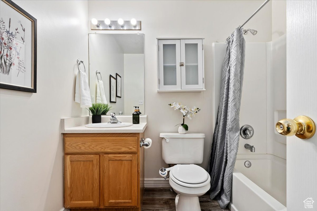 Full bathroom with hardwood / wood-style flooring, toilet, shower / bath combination with curtain, and vanity
