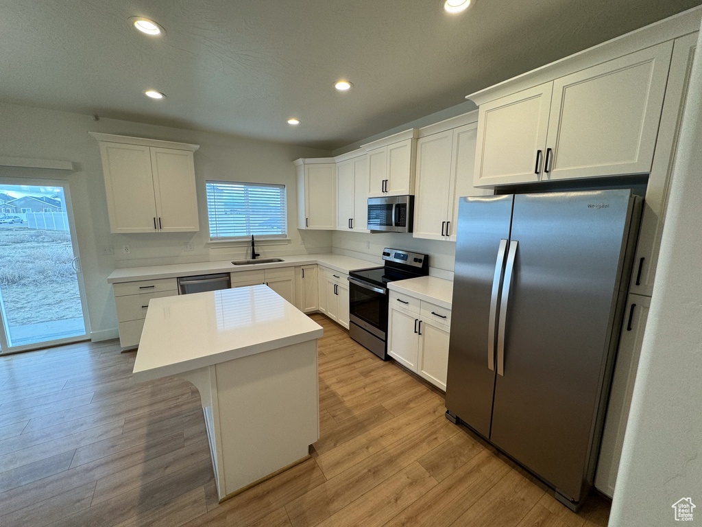 Kitchen featuring a kitchen island, appliances with stainless steel finishes, light hardwood / wood-style flooring, and white cabinets