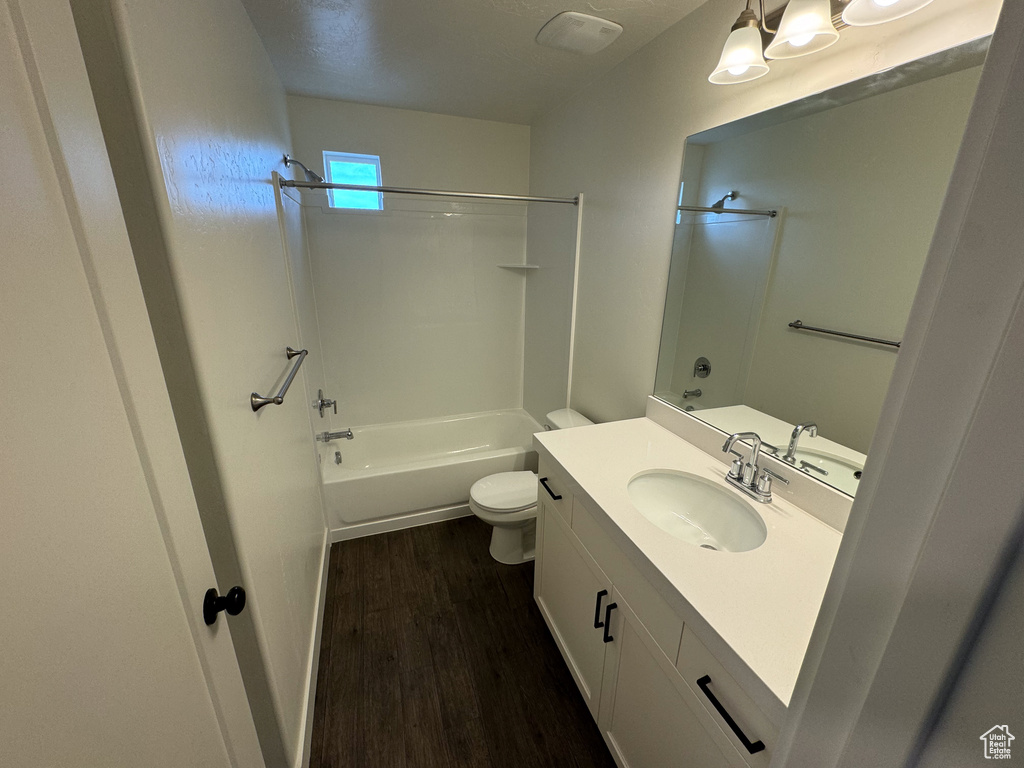 Full bathroom with hardwood / wood-style floors, oversized vanity, shower / bathing tub combination, and toilet