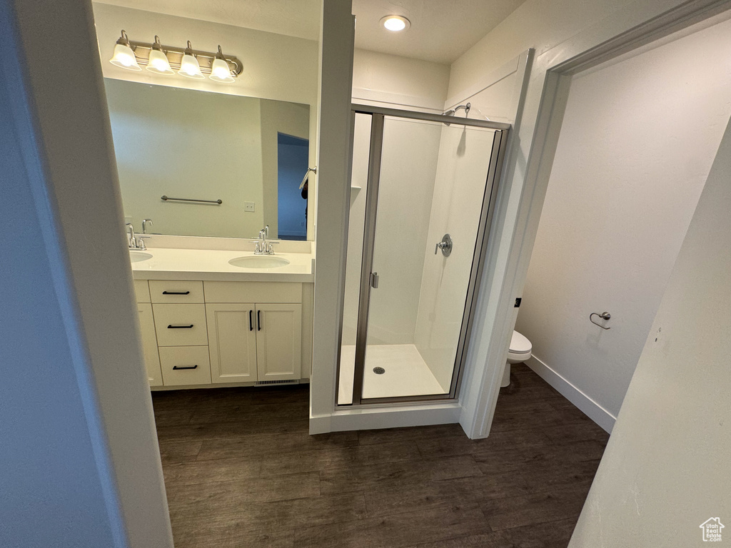 Bathroom with a shower with shower door, toilet, double vanity, and hardwood / wood-style floors