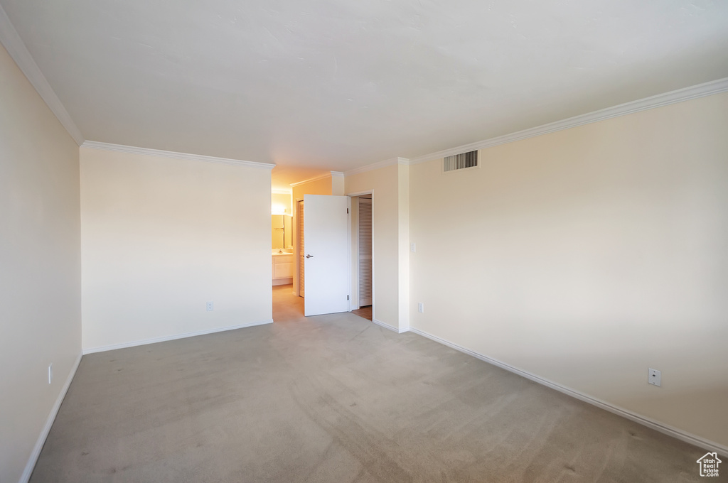 Empty room with ornamental molding and light colored carpet