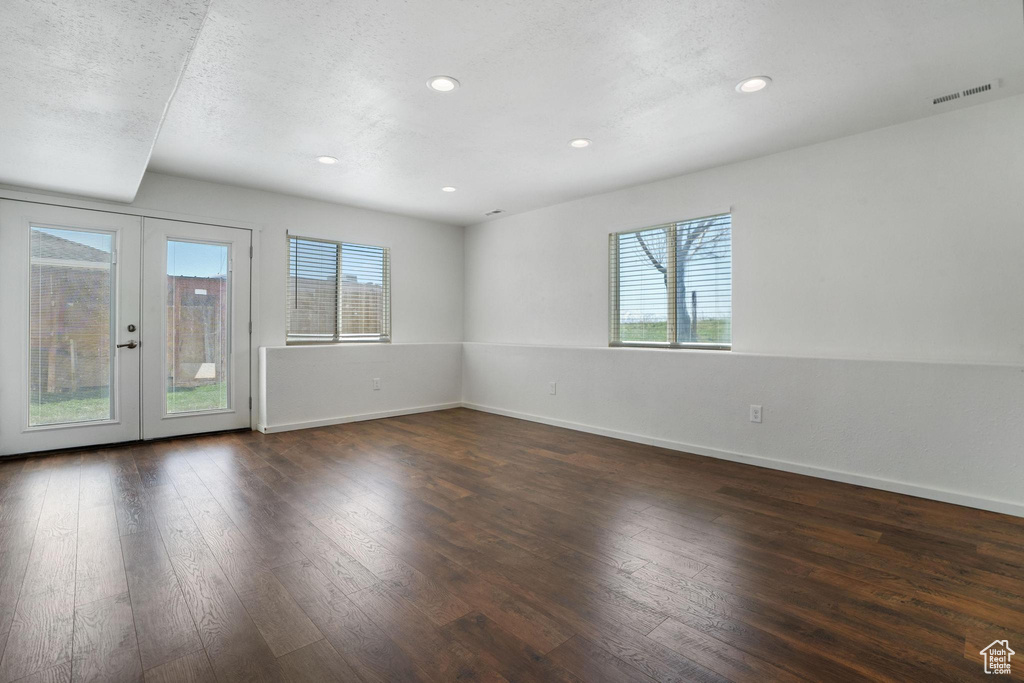 Unfurnished room featuring a textured ceiling, a wealth of natural light, dark wood-type flooring, and french doors