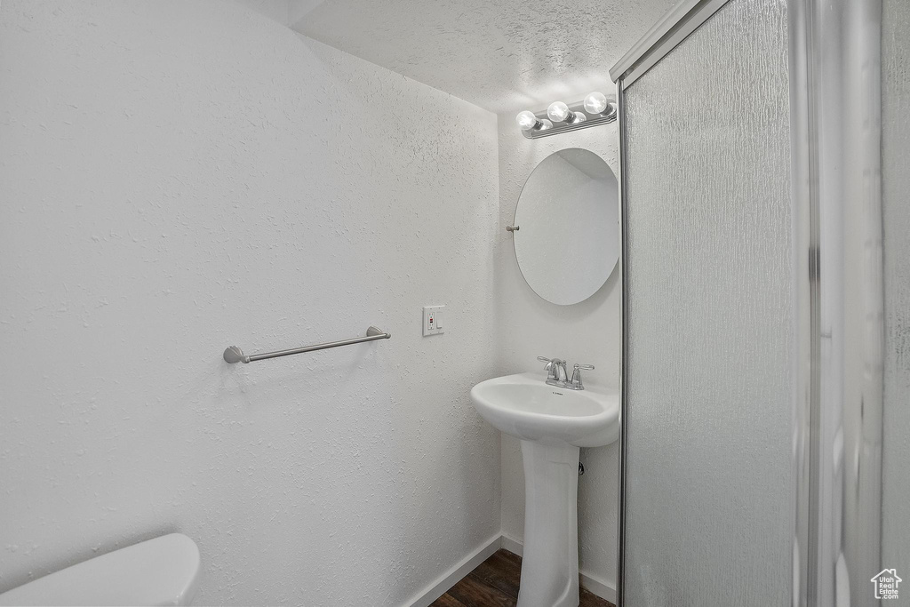 Bathroom featuring wood-type flooring, toilet, and a textured ceiling
