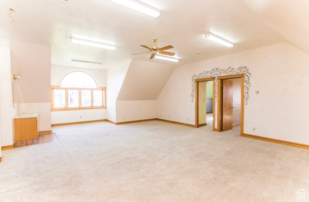 Additional living space featuring vaulted ceiling, ceiling fan, and light carpet