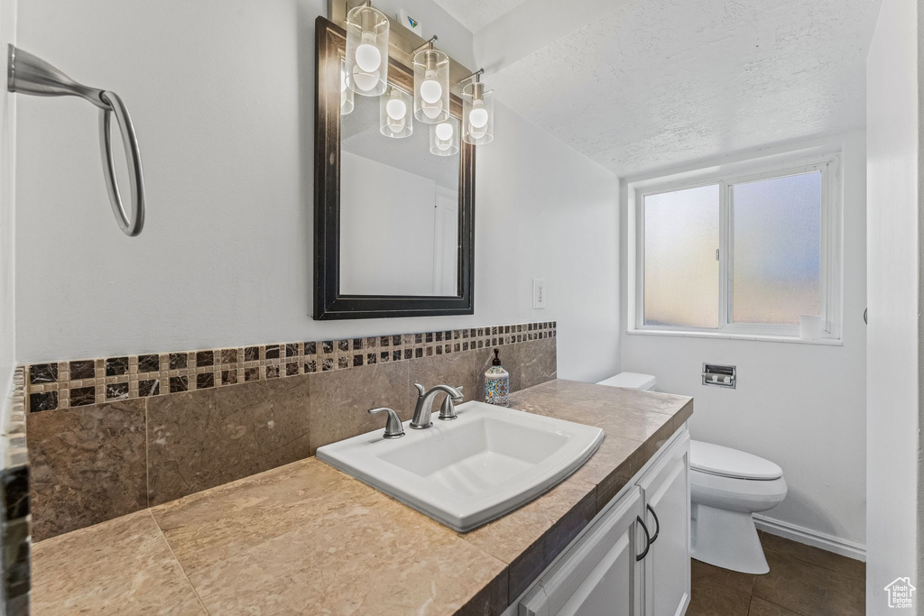 Bathroom featuring tile floors, toilet, oversized vanity, and a textured ceiling