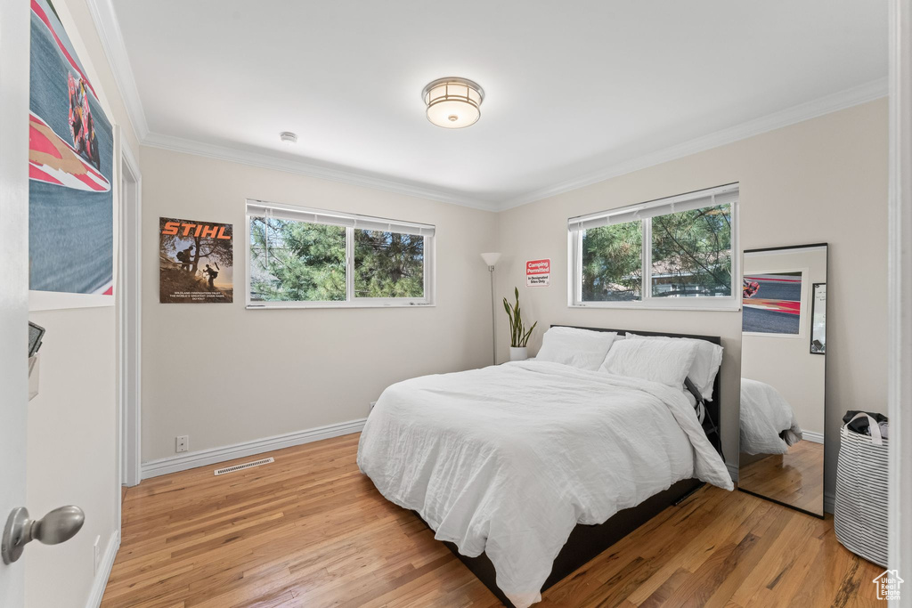 Bedroom with ornamental molding and light hardwood / wood-style floors