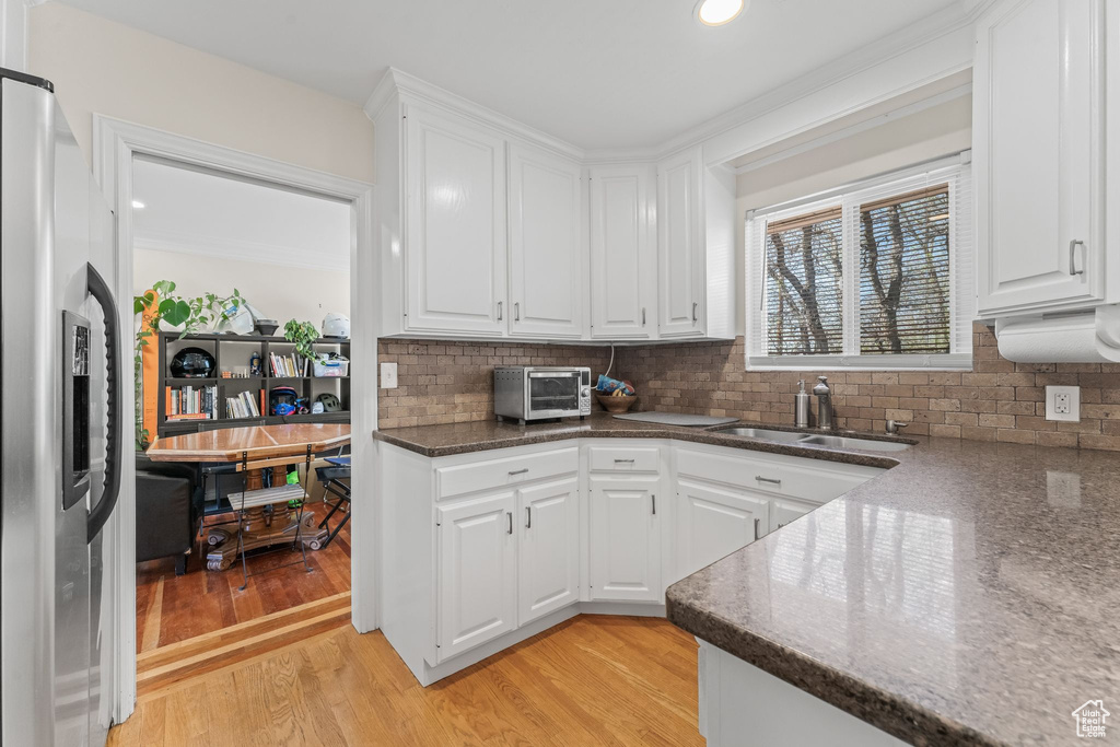 Kitchen featuring white cabinets, sink, light hardwood / wood-style flooring, and stainless steel refrigerator with ice dispenser