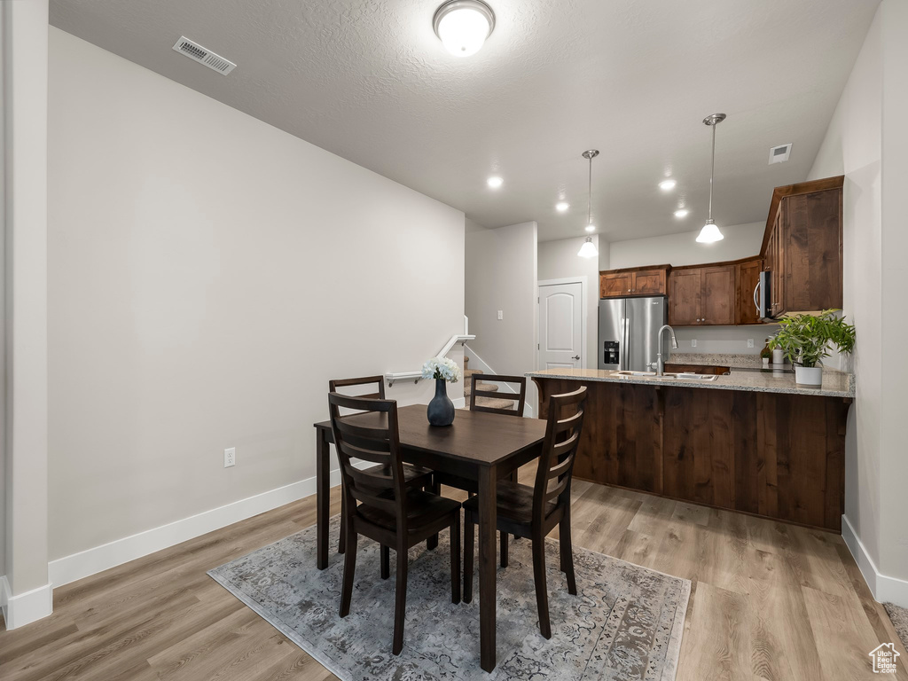 Dining area featuring sink, light hardwood / wood-style floors, and a textured ceiling