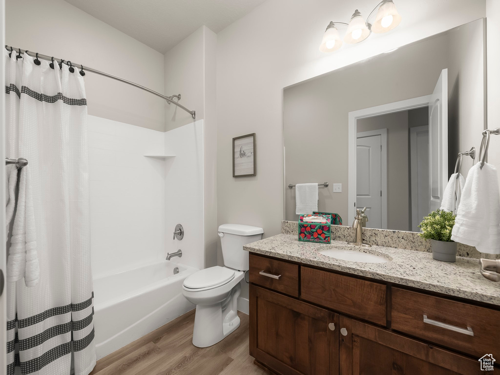 Full bathroom with hardwood / wood-style floors, vanity, toilet, and shower / bath combo