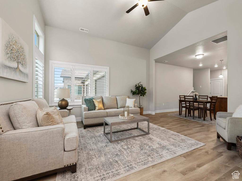 Living room with light hardwood / wood-style floors, vaulted ceiling, and ceiling fan