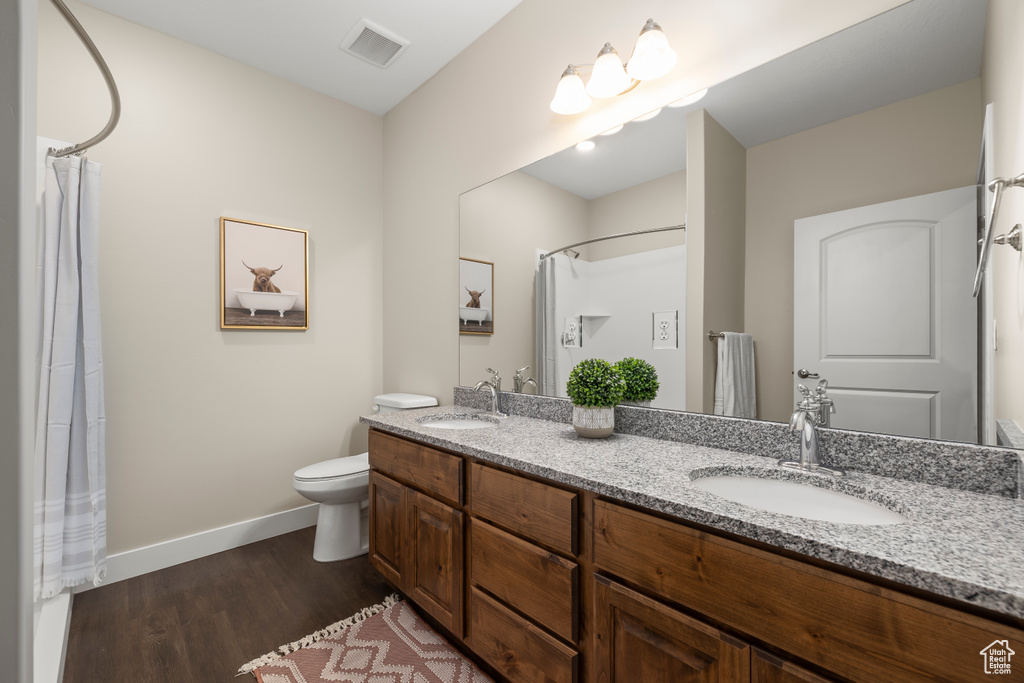 Bathroom featuring hardwood / wood-style flooring, toilet, and dual bowl vanity