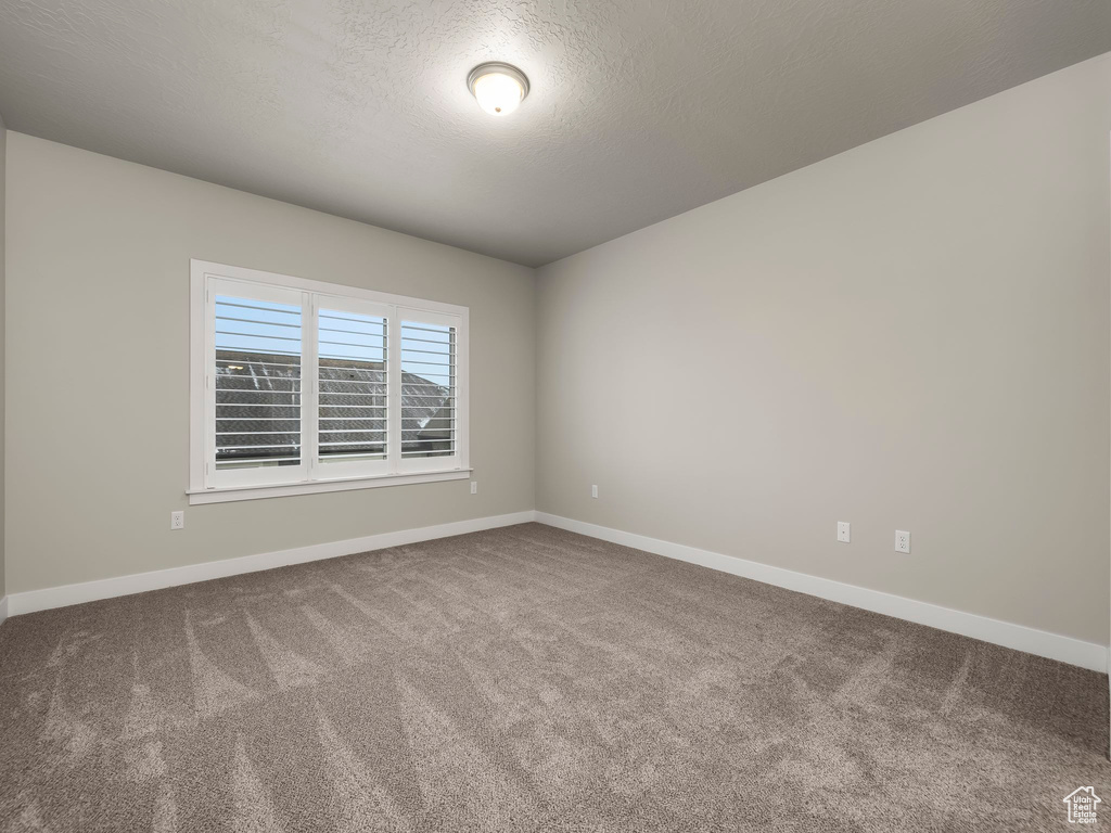 Carpeted spare room featuring a textured ceiling