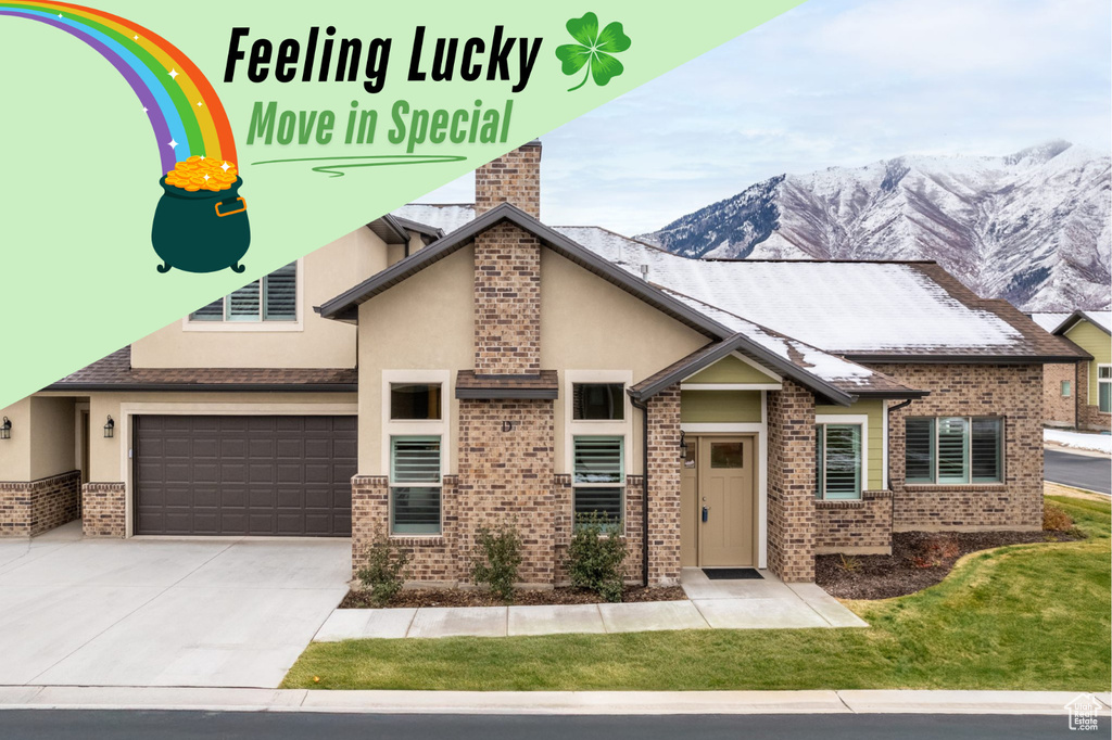 View of front of home featuring driveway, stucco siding, an attached garage, a mountain view, and brick siding