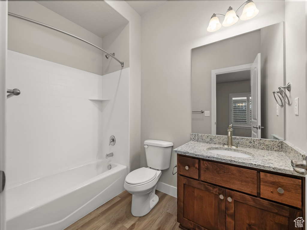 Full bathroom featuring hardwood / wood-style flooring, vanity, toilet, and washtub / shower combination