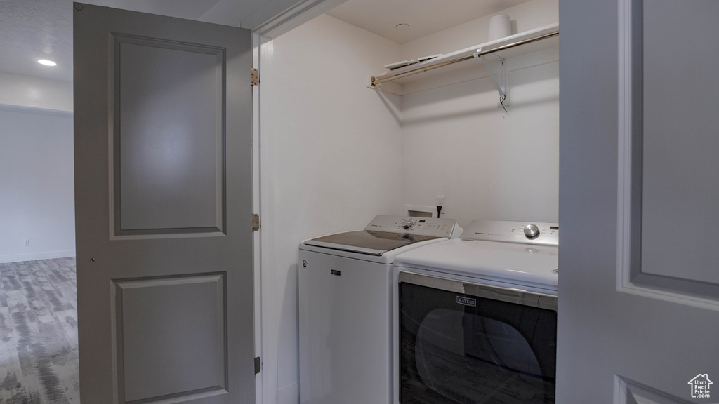 Laundry room with hardwood / wood-style flooring, washer hookup, and washing machine and dryer