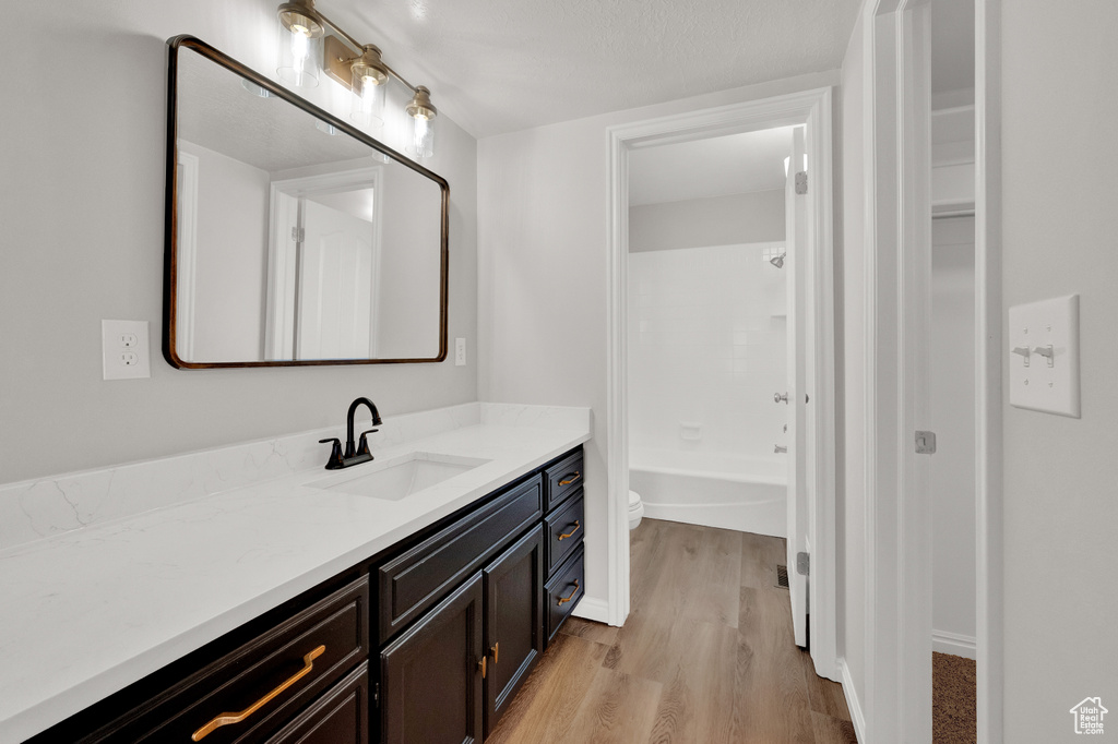 Full bathroom featuring wood-type flooring, bathtub / shower combination, vanity, and toilet
