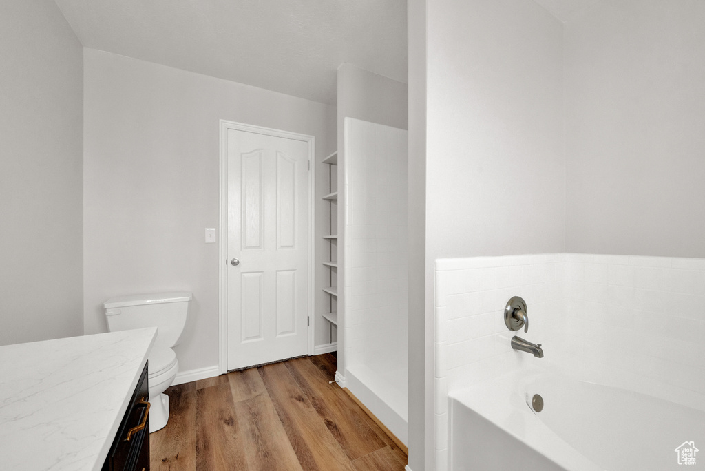 Bathroom featuring a bath, wood-type flooring, vanity, and toilet