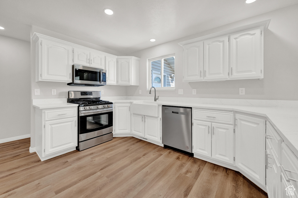 Kitchen featuring appliances with stainless steel finishes, light hardwood / wood-style floors, and white cabinetry