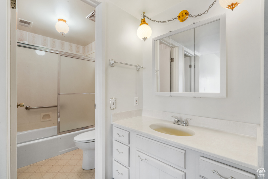 Full bathroom featuring tile flooring, toilet, vanity, and combined bath / shower with glass door