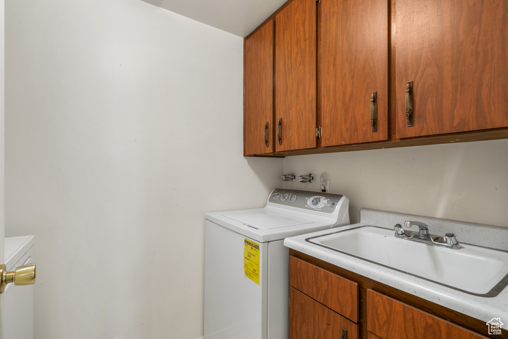 Clothes washing area with washing machine and clothes dryer, cabinets, and sink