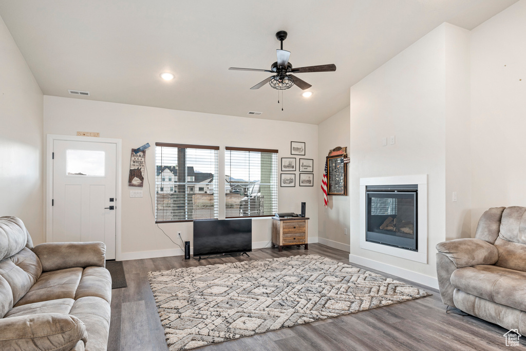 Living room with ceiling fan and dark wood-type flooring