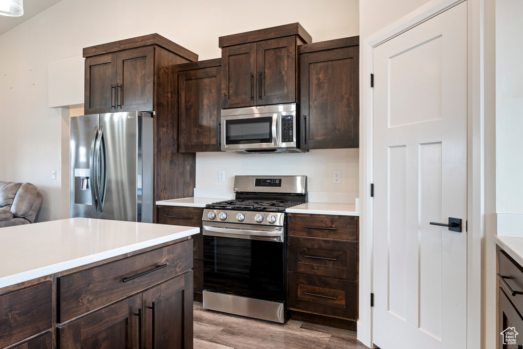 Kitchen featuring appliances with stainless steel finishes, light hardwood / wood-style flooring, and dark brown cabinetry