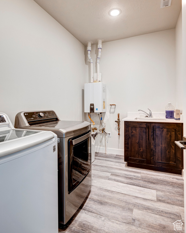 Laundry room with light hardwood / wood-style flooring, sink, separate washer and dryer, and water heater