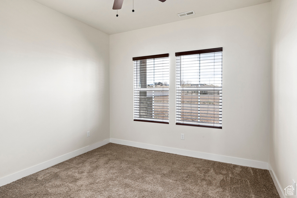 Carpeted spare room featuring ceiling fan