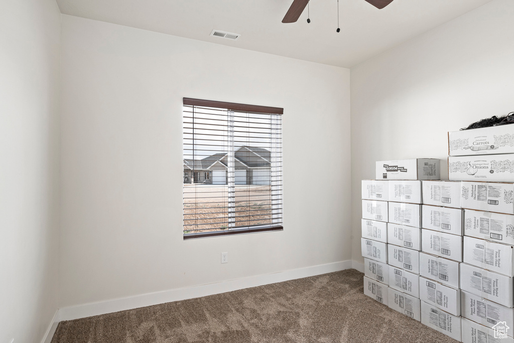 Interior space with dark colored carpet and ceiling fan