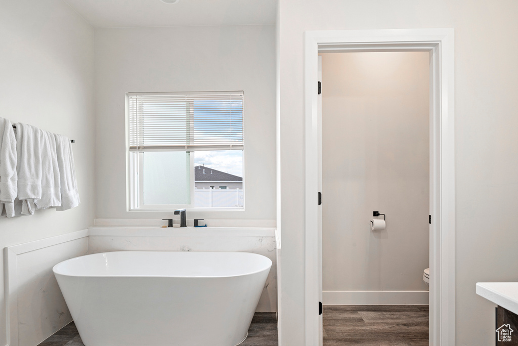 Bathroom featuring hardwood / wood-style flooring, toilet, and a bath