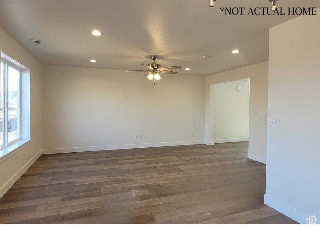 Empty room featuring a healthy amount of sunlight, ceiling fan, and dark hardwood / wood-style floors