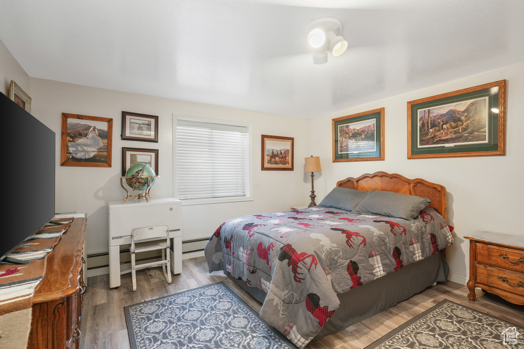 Bedroom with light hardwood / wood-style flooring and a baseboard radiator