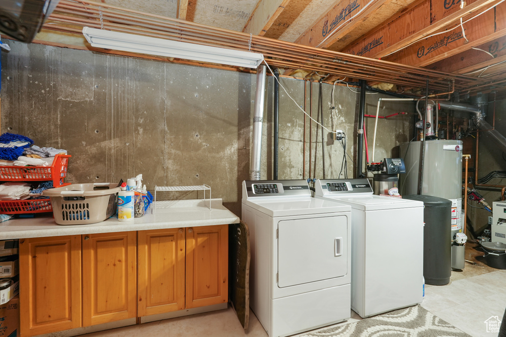 Washroom featuring water heater, cabinets, and separate washer and dryer