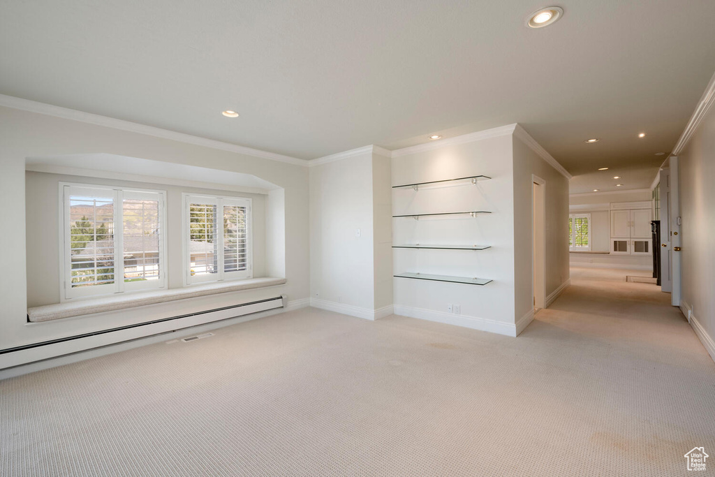 Interior space featuring light carpet, crown molding, and a baseboard heating unit